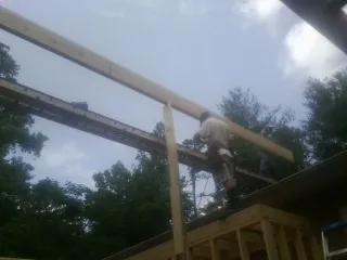 Carpenter setting a ridge beam over a new addition frame — Ice Dam Removal by Roofing Brothers in Bend