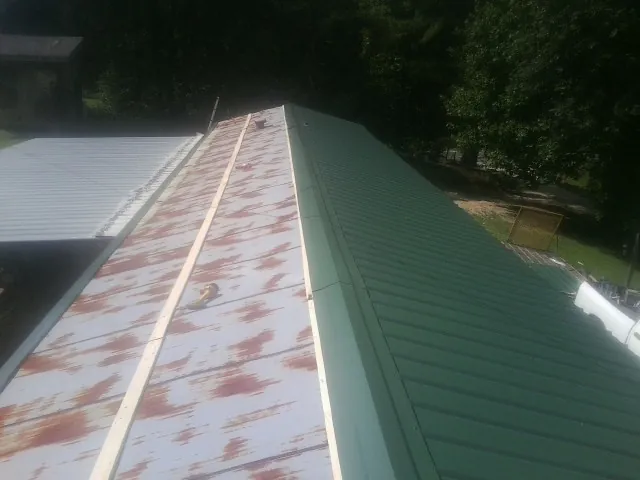 Old rusted panels beside newly installed green metal roofing — Wind Damage Roof Repair by Roofing Brothers in Bend