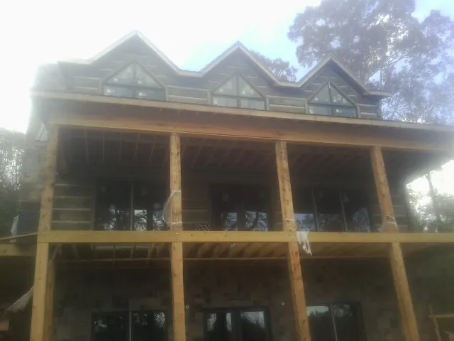 Dormers and porch framing on a large log home under construction — Roof Coating work by our crew in Bend