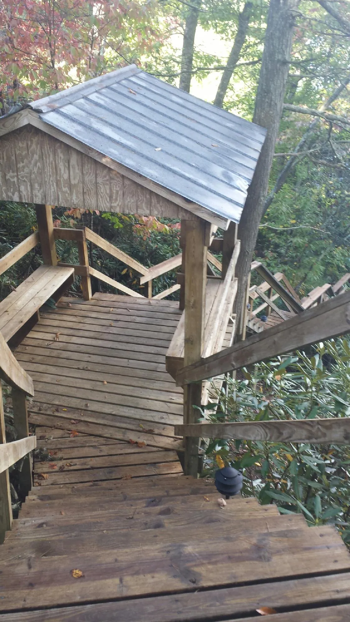 Metal roofed shelter over wooden steps on a wooded walkway — Skylight Repair & Installation work by our crew in Bend